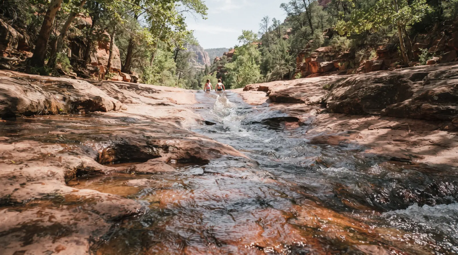 The natural sandstone water slide at Slide Rock State Park with swimmers sliding down the worn Oak Creek chute, Slide Rock State Park Sedona